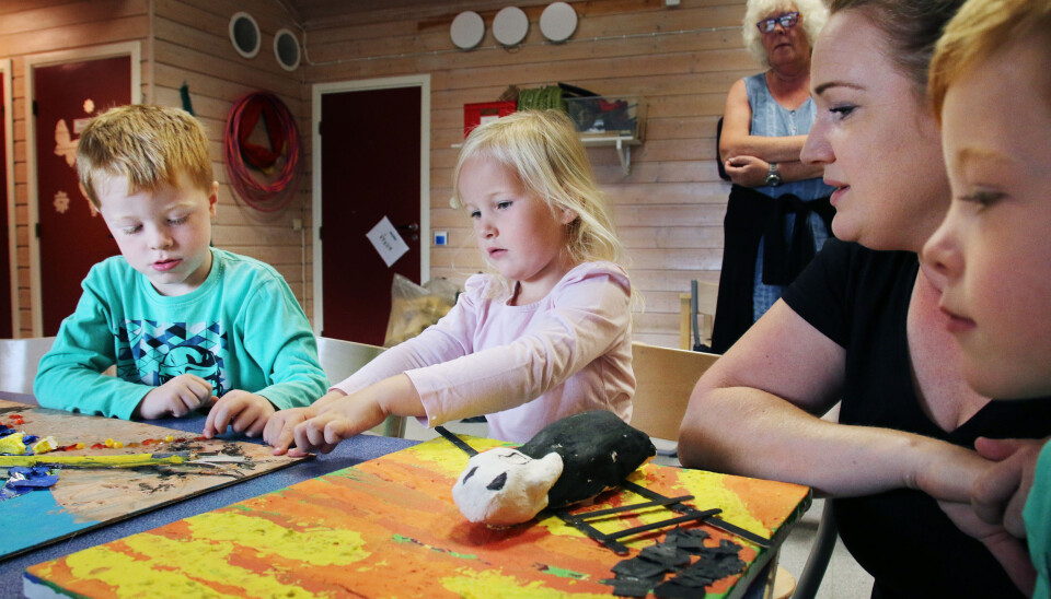 Edvard, Malin og Aksel ser og kjenner på malerier barna har laget inspirert av Munch. Sammen med dem sitter pedagogisk leder Linda Orskaug, og i bakgrunnen står pedagogisk leder Marit Bø Johannessen. Foto: Jørgen Jelstad