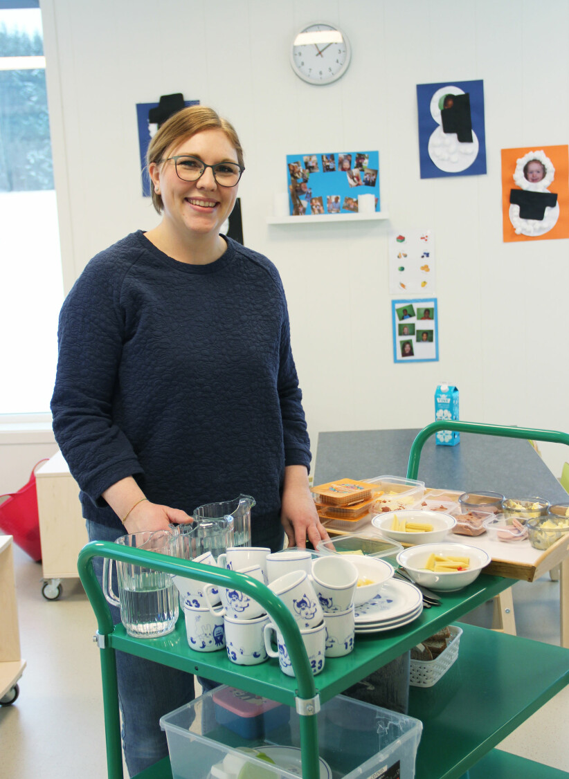 . Assistent Kathrine Kolerud Nilsen gjør klar maten til lunsj og synes det er fint å gjøre praktiske oppgaver i barnehagen. Hun har likevel frihet til å ta med barna for å dekke bordet.