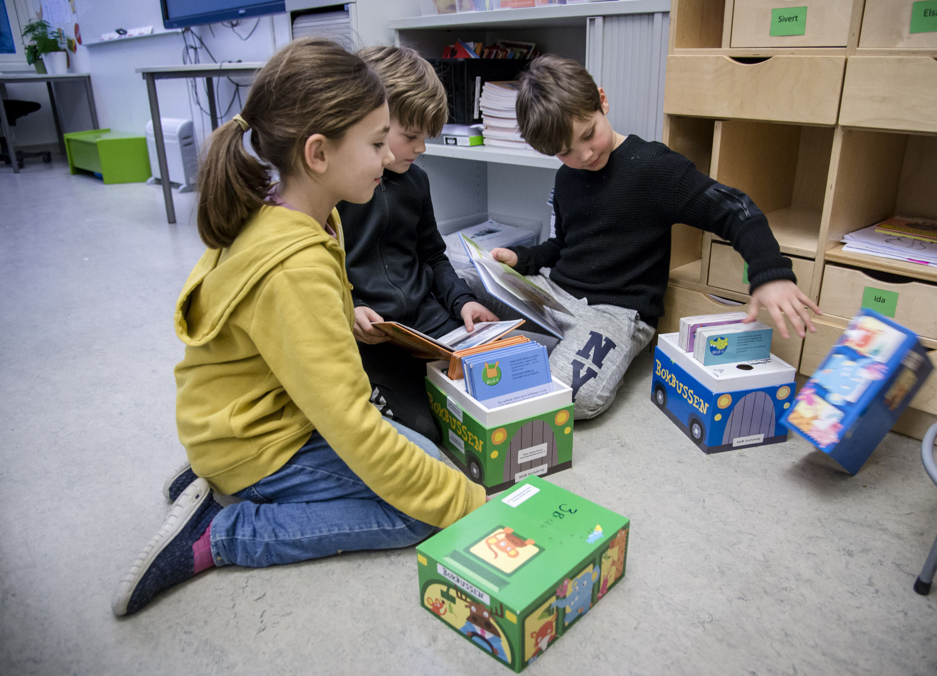 Selma, Jonas og Herman gyver løs på et par bøker gitt til skolen fra Tåsen skoles venner.