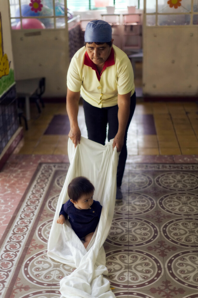BALANSEØVELSE: Det er ikke nødvendig med dyrt materiell for å stimulere barnas utvikling, ifølge den mexicanske barnehagelæreren Ana María. Her drar hun et av barna i et stort laken for å trene balansen.