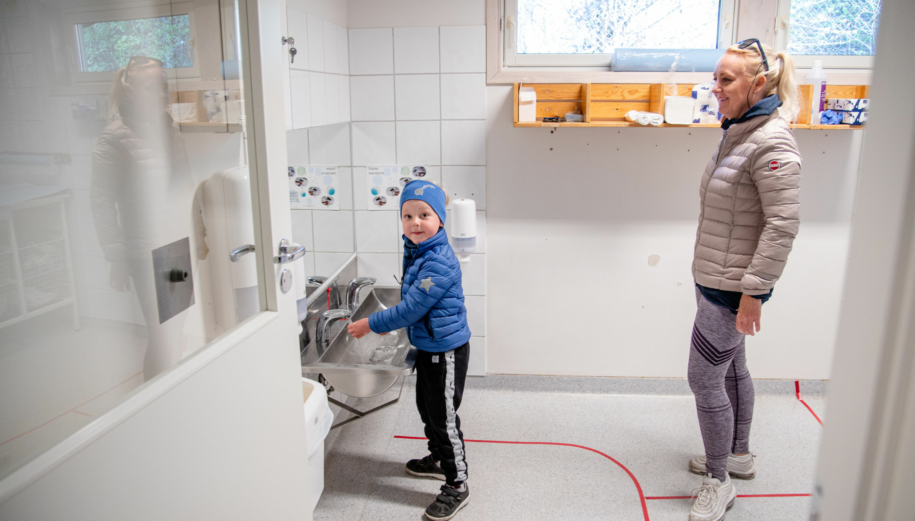 Før han kan begynne å leke, må Aksel Holst Marti vaske hender. Mamma Hanne Holst følger de oppteipede avstandsreglene.