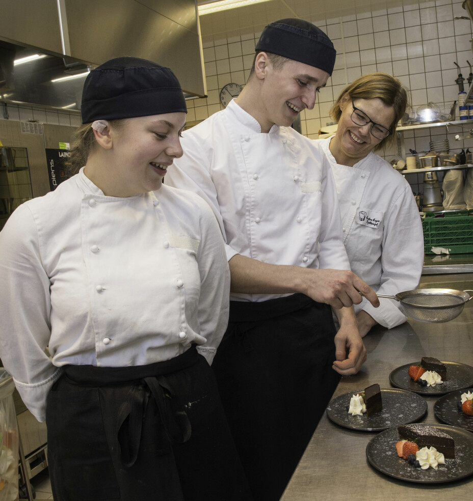 Henrik Owe koser seg med å lage desserter, og her får sjokoladekakene et lett melisdryss. Kjøkkensjef Anne Line Vassbakk Løyning (bak) og lærling Julie Lundberg følger med og lager god stemning.