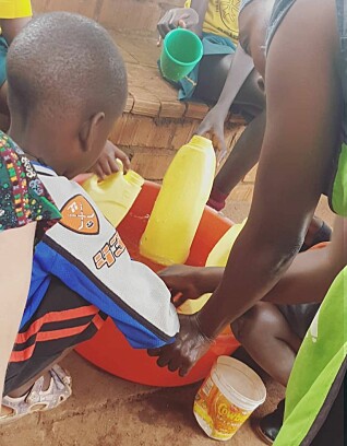 En barnehageansatt i den ugandiske barnehagen setter barn med særlige behov i gang med vannlek.