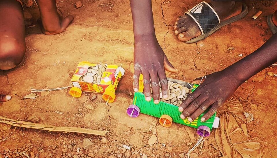 Barna leker i gatene med sand og biler. Leken er den samme enten det er i Norge eller i Uganda.
