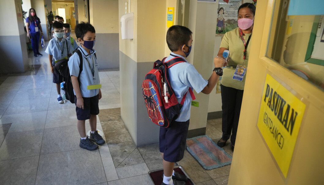 Filippinske skolebarn får sjekket temperaturen før de får slippe inn i klasserommet.