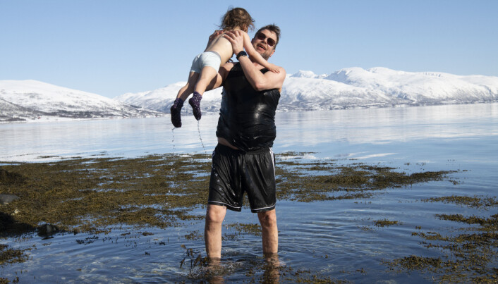 Pedagogisk medarbeider Kenth Mikalsen løfter Sivert (3) opp av vannet og sier det ikke er så stor forskjell å bade om vinteren som i sommerens 13 grader i Tromsø.