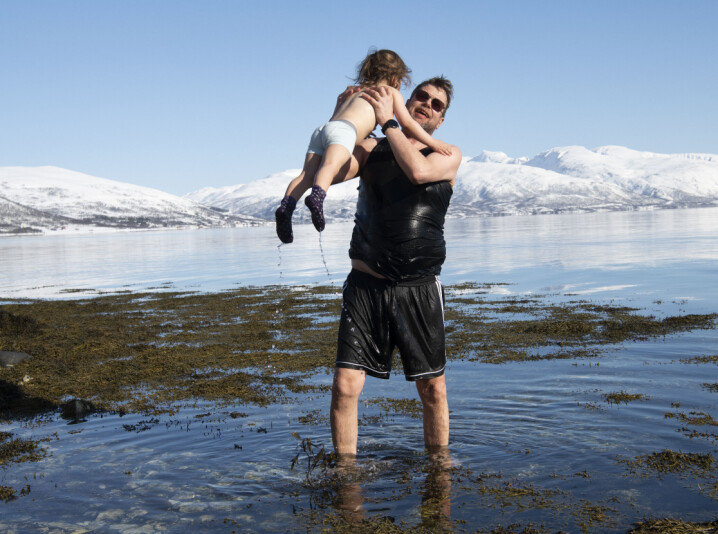 Pedagogisk medarbeider Kenth Mikalsen løfter Sivert (3) opp av vannet og sier det ikke er så stor forskjell å bade om vinteren som i sommerens 13 grader i Tromsø.