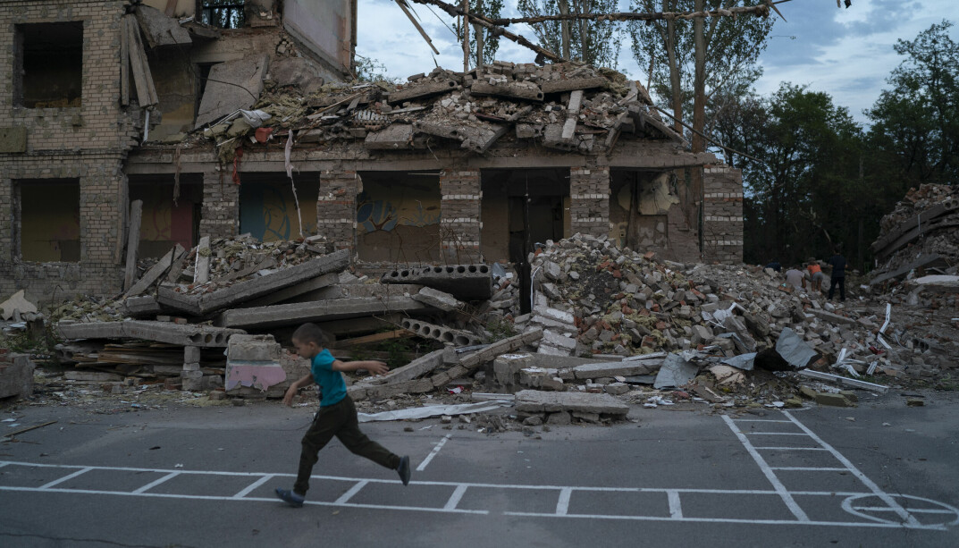 Seks år gamle Oleksij Makarov løper forbi skolebygningen der klasserommet hans lå. Nå leker han og vennene på skoleplassen til den ødelagte skolen. Skolen, som ligger i Kramatorsk, ble smadret i et russisk angrep i midten av Juli. Foto: Leo Correa / AP / NTB