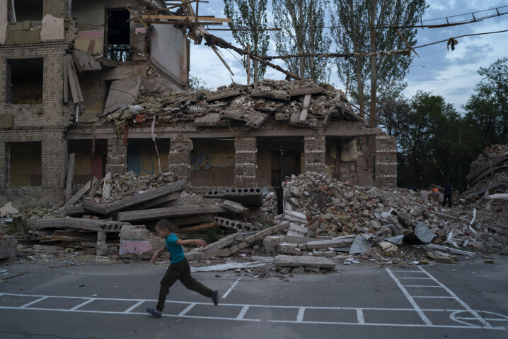 Seks år gamle Oleksij Makarov løper forbi skolebygningen der klasserommet hans lå. Nå leker han og vennene på skoleplassen til den ødelagte skolen. Skolen, som ligger i Kramatorsk, ble smadret i et russisk angrep i midten av Juli. Foto: Leo Correa / AP / NTB