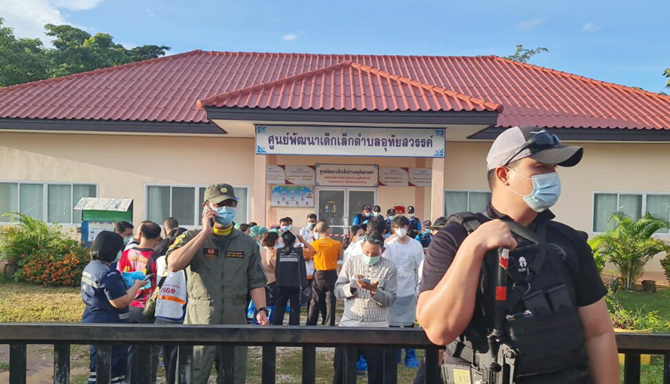 En væpnet politimann vokter porten ved barnehagen i Nongbua Lamphu i Thailand etter skytingen som kostet minst 34 menneskeliv.