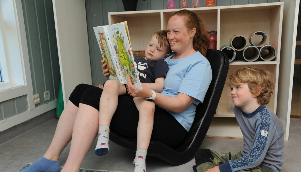 Barnehagelærer Stine Tjøntveit Andersen sitter i en vippestol, som er bra for ryggen, og leser for Jacob Therkelsen og Colin Hubbard Hansen.