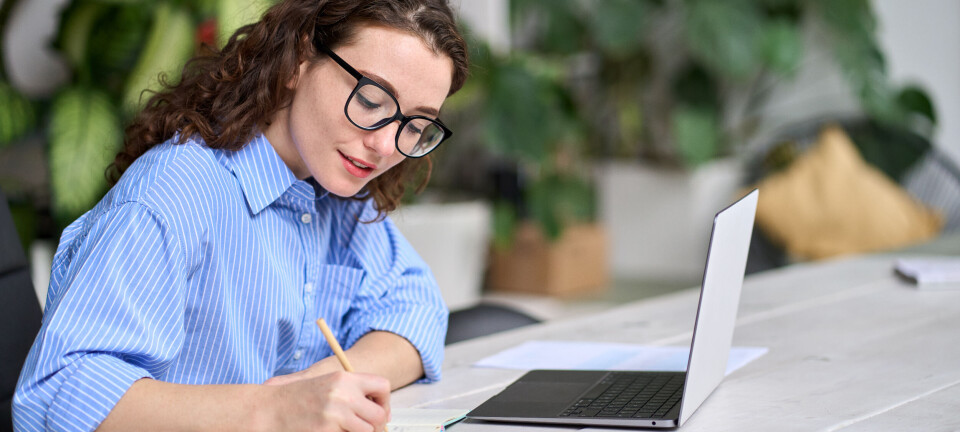Om oss Young business woman worker using laptop writing notes, female employee sitting at desk in office watching online webinar training or web course, doing research, working or elearning at workplace.