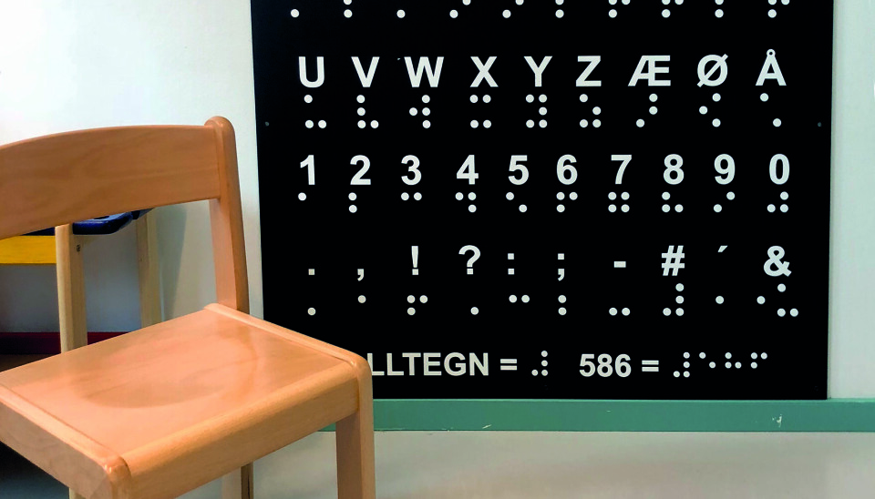 På veggen i en barnehage er det en stor tavle som viser alfabetet både i punkt- og visuell skrift.