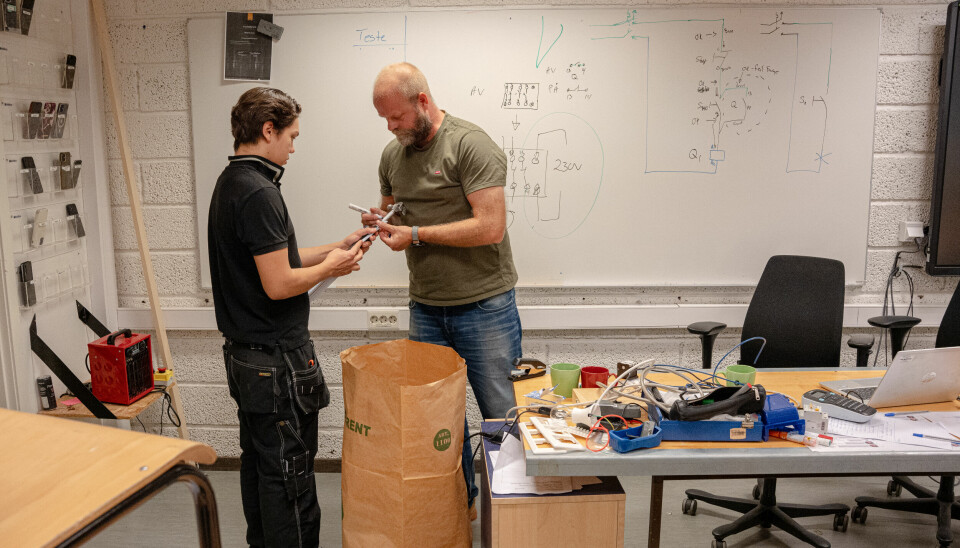Petter Garder setter et merke på hammeren til vg2-elev Ellis Achille, slik at den kan brukes til å måle avstand med.