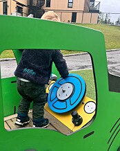 Barn gutt lekeplass grønn lekebil ratt lekeapparat lek utelek barnehage uteområde