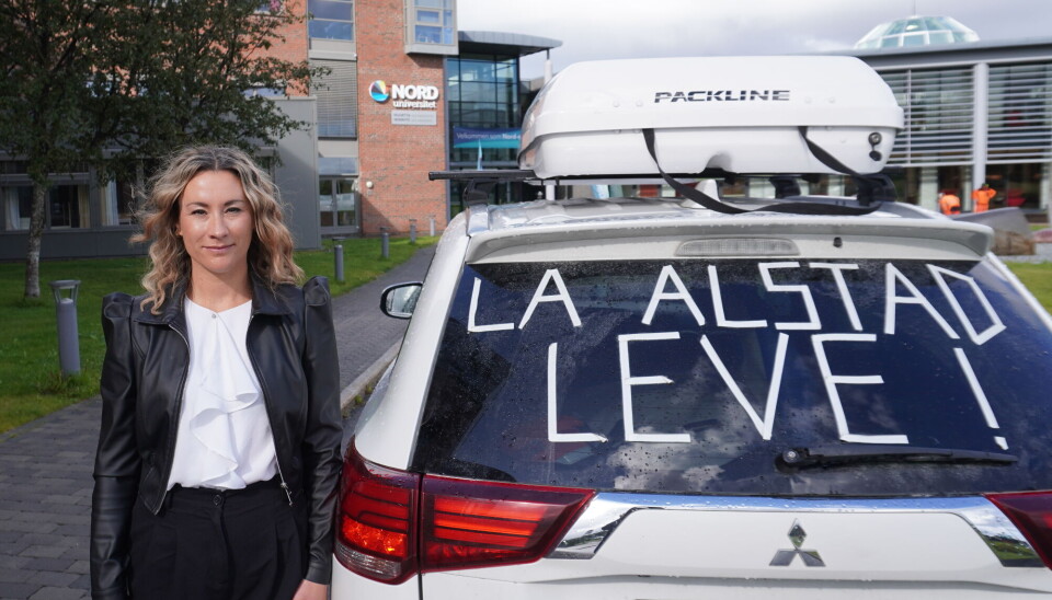 Alstad er en av to barneskoler i Bodø som trues med å legges ned. Hanne Gravrok, seniorrådgiver ved Nord universitet, står foran universitetet med en hvit bil ved siden av der det står 'La Alstad Leve'