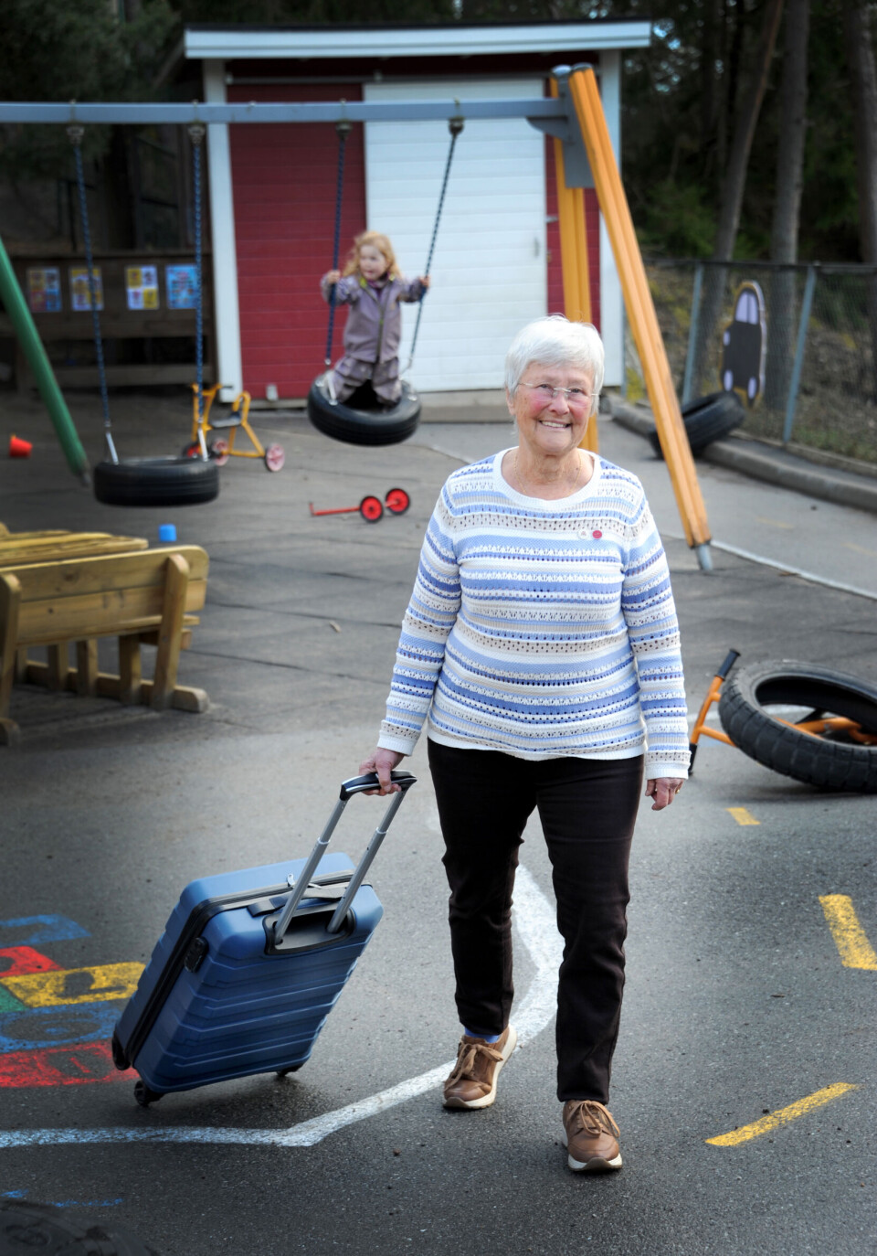 Barna er fascinerte av Gros blå trillekoffert, der hun har bøker hun skal lese for barna i Ullerøy barnehage.