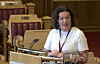 En kvinne står ved talerstolen i Stortingets sal med mikrofon. Hege Bae Nyholdt fra Rødt.