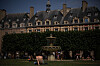 Besøkende sitter og hviler i parken på Place des Vosges med fontene og historiske bygninger i bakgrunnen.