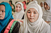Ung kvinne i lys hijab sitter fremst blant flere kvinner i hijab.