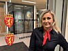 Kvinne i mørk jakke og rødt skjerf foran inngangen til Riksmekleren og Arbeidsretten.
