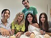 Fem personer samlet rundt et bord med mat, med en person i grønn T-skjorte bakerst.