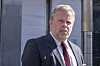 Jon Wessel-Aas i mørk dress utenfor en moderne bygning.