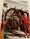 Inger Alsaker som barn står ved et stort treskipsratt på et fartøy.