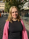 Maja Fjellvær Thompson står på en brosteinslagt plass iført rosa jakke og svart topp.