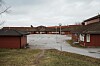 Tom, våt skolegård omgitt av røde skolebygninger og grå himmel.